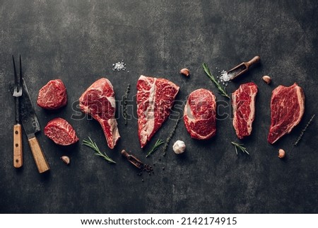 Various types of raw pork meat and beef on black board