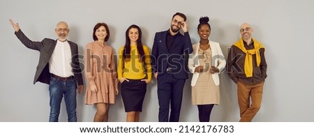 Happy people in clothes suitable for office dress code standing in studio. Mixed race multiethnic group of male and female models in stylish smart casual outfits and glasses posing against grey wall Royalty-Free Stock Photo #2142176783