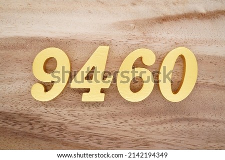 Wooden  numerals 9460 painted in gold on a dark brown and white patterned plank background.