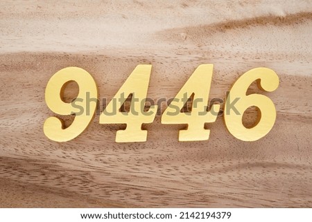 Wooden  numerals 9446 painted in gold on a dark brown and white patterned plank background.