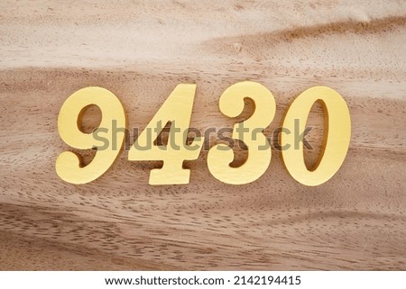 Wooden  numerals 9430 painted in gold on a dark brown and white patterned plank background.
