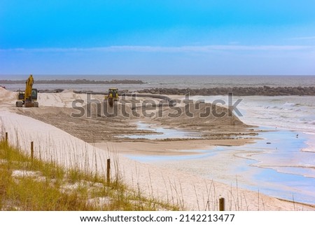 Heavy equipment replenish shoreline with sand as it's dredged from the pass Royalty-Free Stock Photo #2142213477