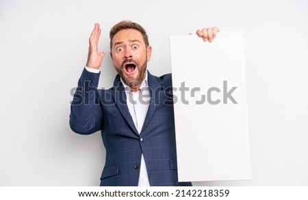 middle age handsome man screaming with hands up in the air. copy space concept