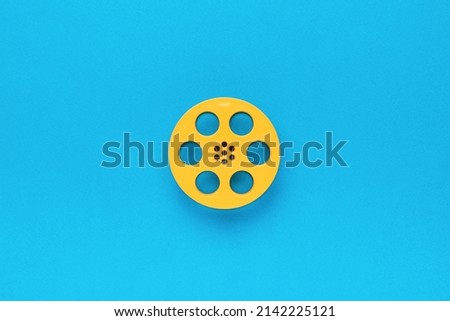 Plastic film reel on a blue background. The minimal concept of cinema. Flat lay.