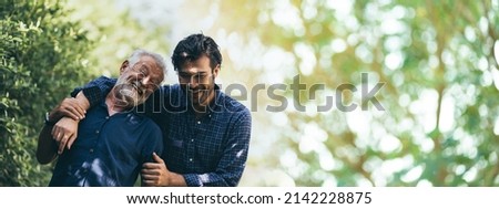 senior father hugging adult hipster son, have a happy feeling together, elderly caucasian person man or grandfather smiling with love in concept of family at home nature outdoor garden, banner space Royalty-Free Stock Photo #2142228875