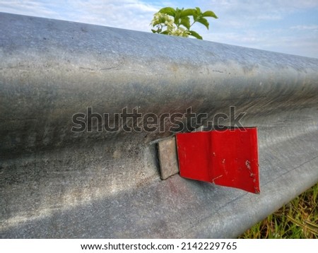 The road divider is made of iron with a little red color so that it is easy for car drivers to see
