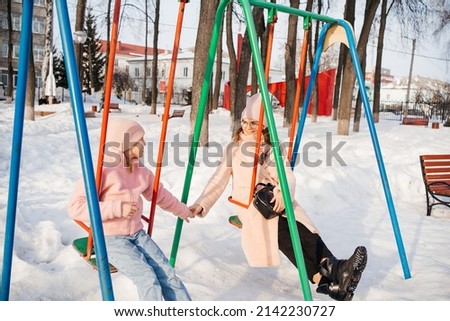 mother and daughter ride a swing in the park on a spring day. High quality photo