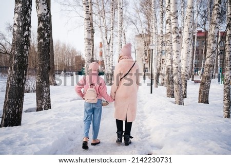 mother and daughter walk in the park on a spring sunny day view from the back. High quality photo