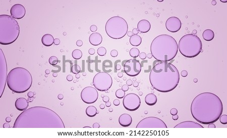 Macro shot of purple different sized transparent oil drops floating in clear liquid on light purple background | Background for skin care product Royalty-Free Stock Photo #2142250105