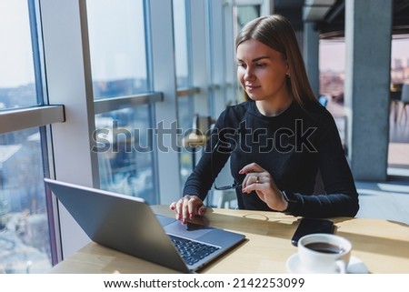 Portrait of a European young and successful woman sitting in a modern cafe with laptops. Pretty female freelancer is enjoying her free time in a cafe.