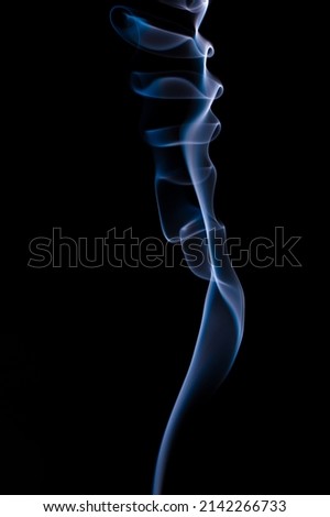 Blue and grey smoke patterns from incense stick and cigarette smoke taken in a studio on a black backdrop beautifully isolated  