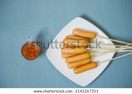 Cooked smoked chicken sausage skewers on a plate with dipping sauce