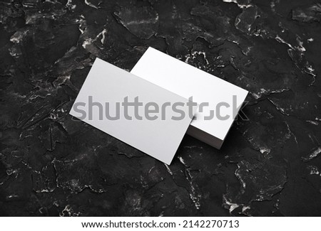 Blank white business cards on black plaster background. Mockup for branding identity. Template for graphic designers portfolios.