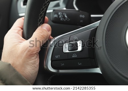 Cruise control and volume buttons on modern car steering wheel, interior details with driver hand Royalty-Free Stock Photo #2142285355
