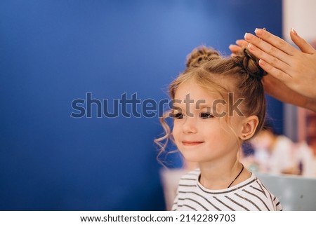 Portrait of a little beautiful girl with a stylish hairstyle in a beauty salon. The process of making a child's hair