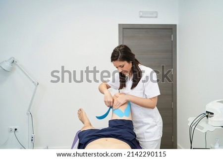 physiotherapist treating the patient's knee with neuromuscular taping Royalty-Free Stock Photo #2142290115