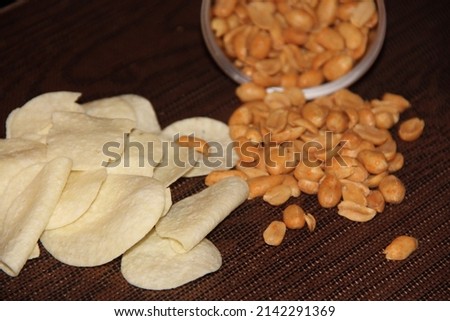 A scattering of salted peanuts and potato chips on a dark background