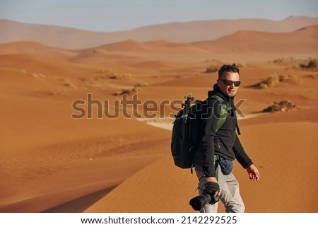 Photographer is working. Male tourist in casual clothes is in the deserts of Africa, Namibia.