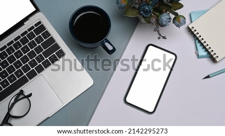 Mobile phone with blank screen, laptop computer, coffee cup and notebook on white table. Flay lay.