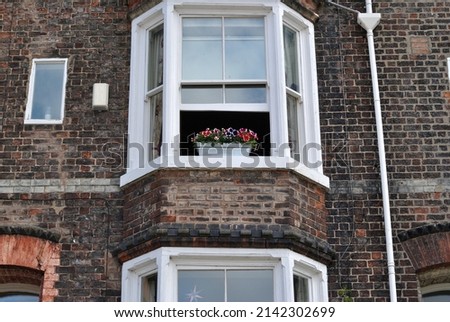 Planter with Colourful Flowers on Sill of Open Window in Old Brick House  Royalty-Free Stock Photo #2142302699