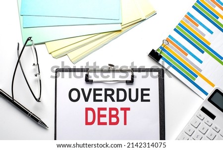 OVERDUE DEBT text on a paper sheet with chart,color paper and calculator