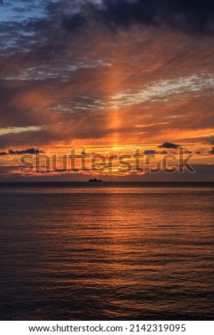 Viewed from a famous island, a vertical photo of a dramatic glowing ocean sunset sky over the Japan Sea.
