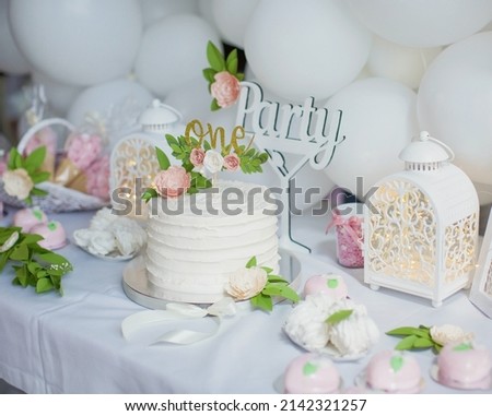 First birthday cake with white cream, golden cake topper with paper flowers. White birthday party for little girl