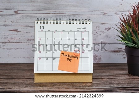 November 2022 calendar on wooden desk with date circle and text on sticky note. Thanksgiving Day on 25th November 2022.