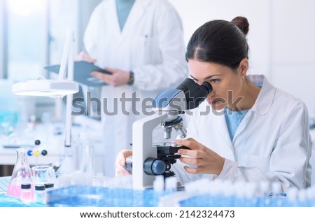 Students working in the clinical laboratory, a researcher is using a microscope in the foreground, scientific research concept Royalty-Free Stock Photo #2142324473
