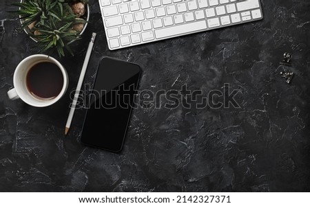 Top view of work space with keyboard, smartphone, coffee cup, succulent plant and pencil on black plaster background. Flat lay.