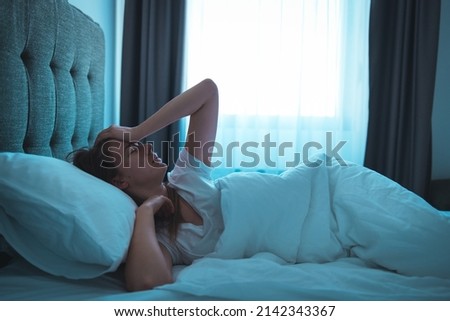 Photo of a young woman lying in bed at night, wide awake with a case of insomnia. Sleep disorder, insomnia. Young blonde woman lying on the bed awake  Royalty-Free Stock Photo #2142343367