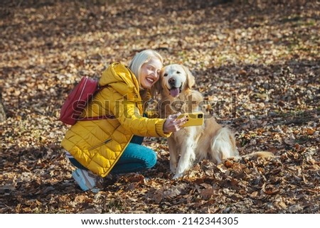 Photo of a young woman making selfie with her dog. Woman taking selfies with pet dog in park. She cuddles her beloved pet. Newer alone when you have dog