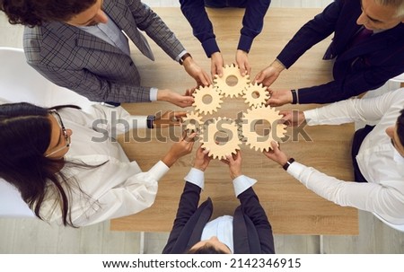 Entrepreneurs, office workers or business partners stacking wooden gears next to each other, symbolizing development and success. Concept of teamwork and business cooperation. Top view. Royalty-Free Stock Photo #2142346915