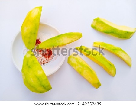 Close up of Mango slices isolated on white background. Mangoes slices. Unripe mangoes slices on white background with spicy mixture of salty and chillies powder. With selective focus on the subject.