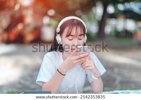Listening to music. A beautiful woman with headphones is relaxing on her desk. She is listening to music using her smartphone, chill and relaxation concept.