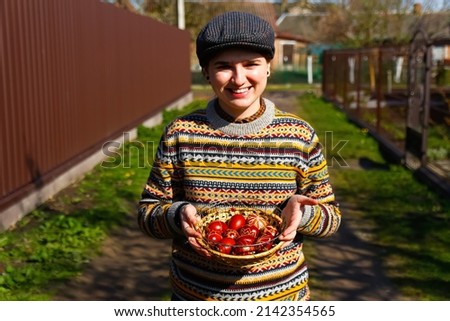 Defocus ukrainian young smiling woman in hat holding plate of collection of red egg on nature background. Easter, Ukraine. Craft painted eggs. Pysanka or krashanka. Happy Easter. Out of focus. 