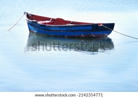 Not a breath of wind today. Shot of an empty fishing boat floating on calm waters. Royalty-Free Stock Photo #2142354771