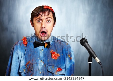 Looks like the jokes on him. Portrait of a bad standup comedian covered in rotten tomatoes. Royalty-Free Stock Photo #2142354847