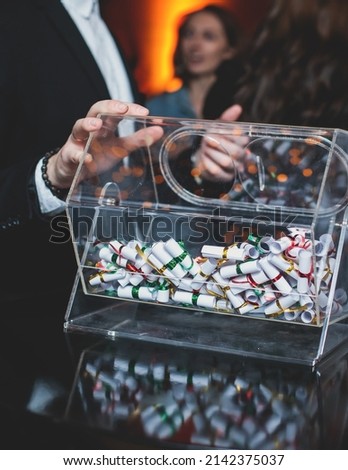 Process of prize drawings, extracting a winning numbers of lottery machine, raffle drum with a bingo balls and winning tickets on event with a host and hands on lottery machine
 Royalty-Free Stock Photo #2142375037