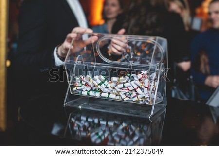 Process of prize drawings, extracting a winning numbers of lottery machine, raffle drum with a bingo balls and winning tickets on event with a host and hands on lottery machine
 Royalty-Free Stock Photo #2142375049