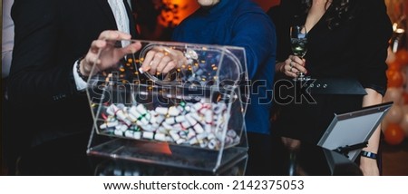 Process of prize drawings, extracting a winning numbers of lottery machine, raffle drum with a bingo balls and winning tickets on event with a host and hands on lottery machine
 Royalty-Free Stock Photo #2142375053