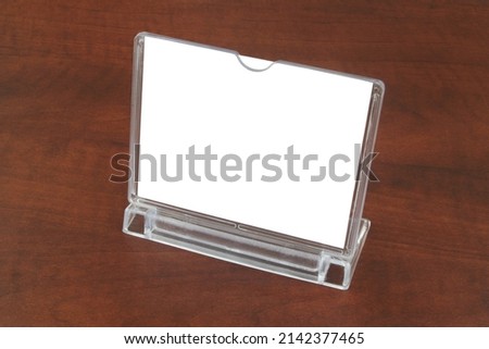 Transparent desk display on wooden table. Advertising stand or banner with copy space for text. Mock up template.