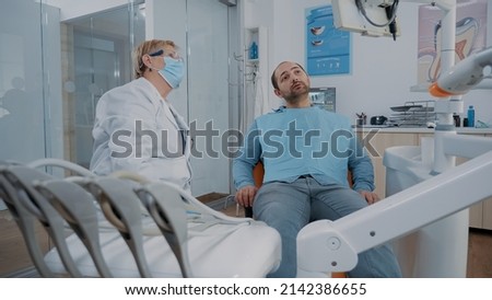 Orthodontist pointing at teeth radiography on monitor to show caries diagnosis to patient in pain. Dentist explaining x ray scan and stomatological procedure to cure toothache.