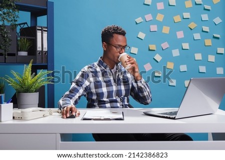 Marketing company project manager reviewing management plan and statistics using work laptop while sitting at desk. Young entrepreneur enjoying coffee while preparing startup project presentation. Royalty-Free Stock Photo #2142386823