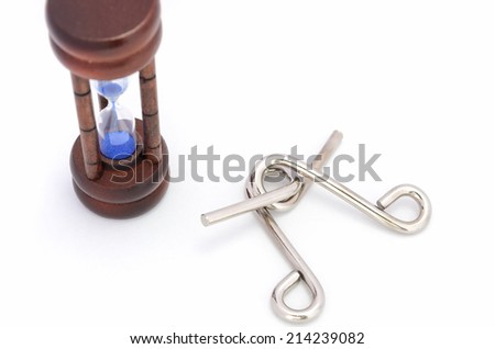Wire puzzle (Puzzle ring)  and Hourglass on a white background.