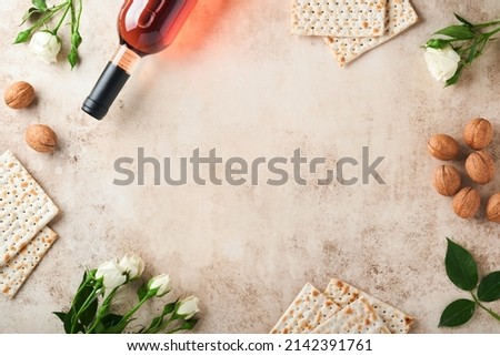 Passover celebration concept. Matzah, red kosher walnut and spring beautiful rose flowers.. Traditional ritual Jewish bread on sand color old concrete background. Passover food. Pesach Jewish holiday. Royalty-Free Stock Photo #2142391761