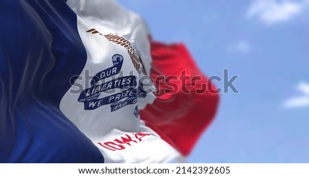 The US state flag of Iowa waving in the wind. Iowa is a state located in the midwestern region of the United States. Democracy and independence. Royalty-Free Stock Photo #2142392605