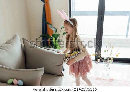 happy caucasian toddler girl eight years old at home in living room with colored easter eggs. Stay home during Coronavirus covid-19 pandemic