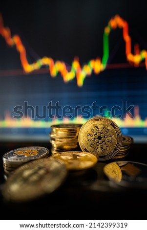 Stack or heap of gold IOTA (MIOTA) cryptocurrency with candle stick graph chart and digital background.