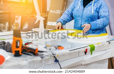 Applying colored yellow membrane to a surface of plastic 3d letter of signboard. worker's hands close up